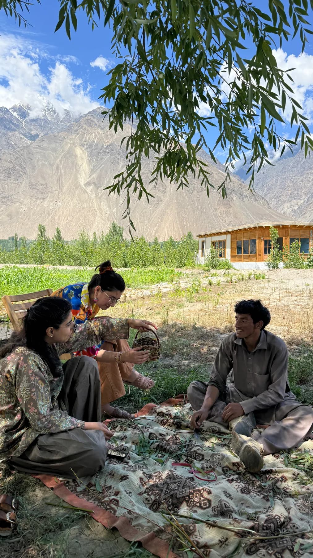 Guests learning willow weaving on a rug in the garden