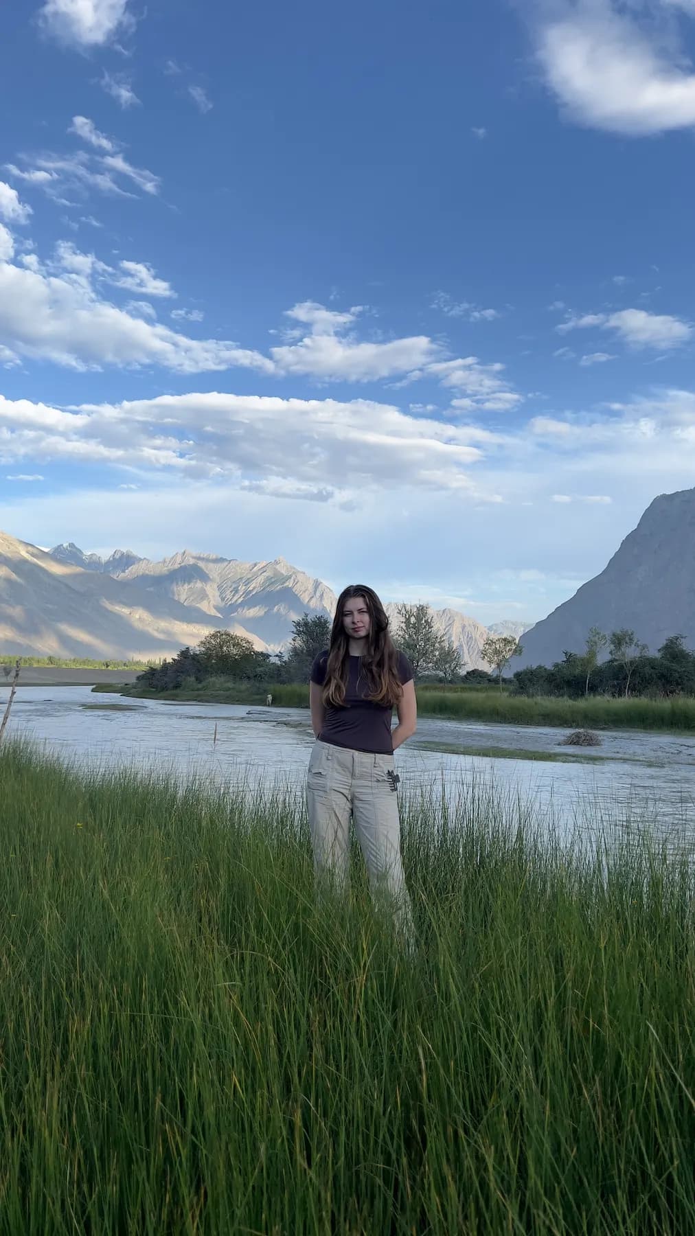 A guest standing in tall grass by the river